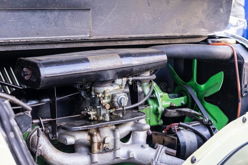 Närbild på en klassisk bilmotor med förgasare och gröna fläktblad.